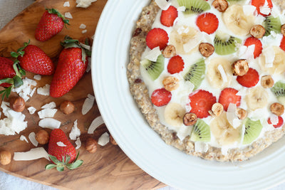 Pizza dolce di porridge con frutta fresca, nocciole e scaglie di cocco